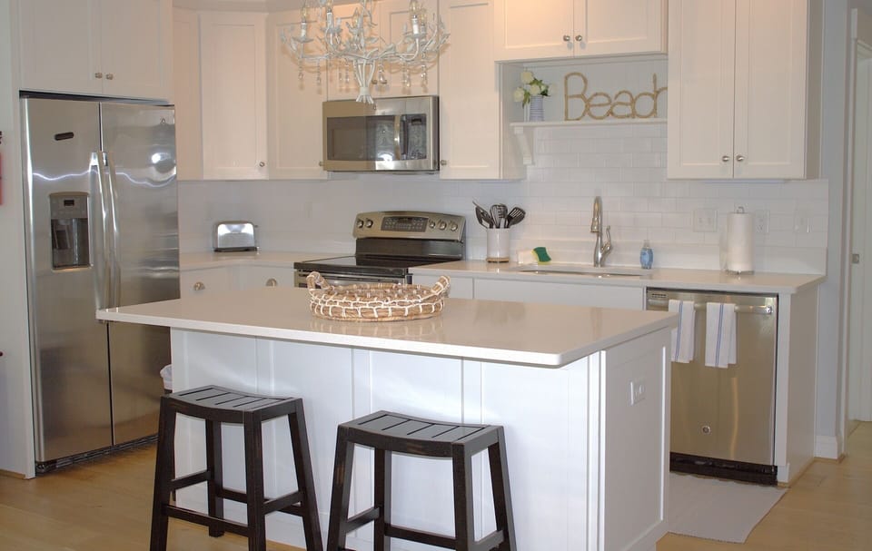 Fully-equipped kitchen features white cabinetry and a spacious island with barstool seating.
