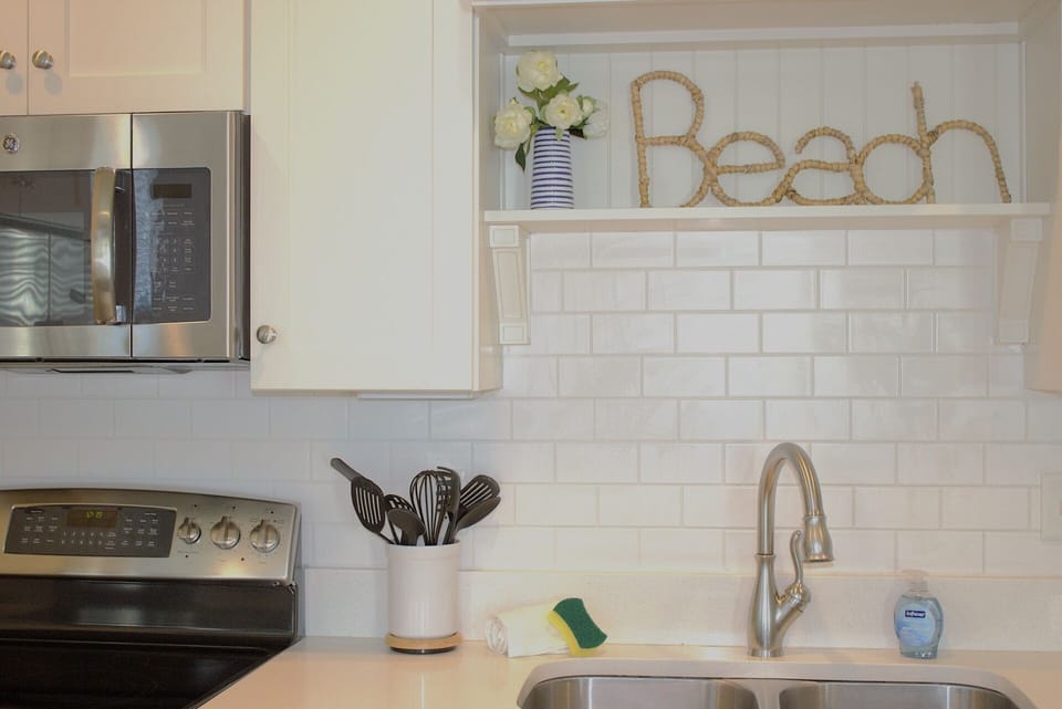 Elegant white design with stainless steel appliances and subway tile backsplash.