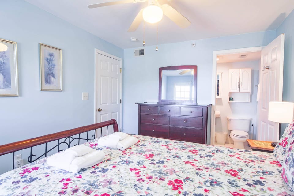 The en suite bathroom is located through the door to the right of the dresser.