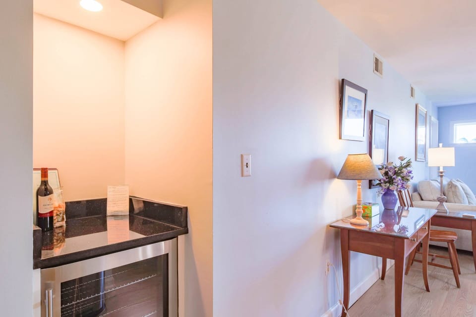 There's a small drink refrigerator and countertop near the dining table and living room.