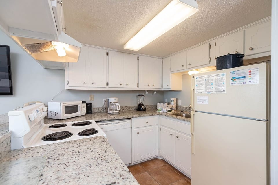 This kitchen features white cabinetry, granite countertops, and essential appliances for a delightful cooking experience
