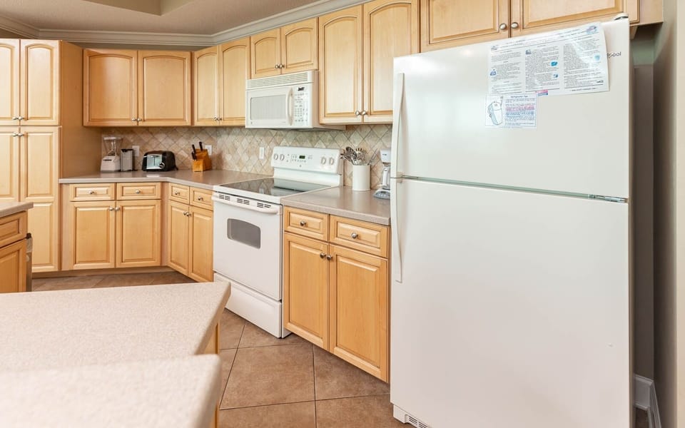 Kitchen featuring light wood cabinetry, white appliances, and ample counter space for meal preparation