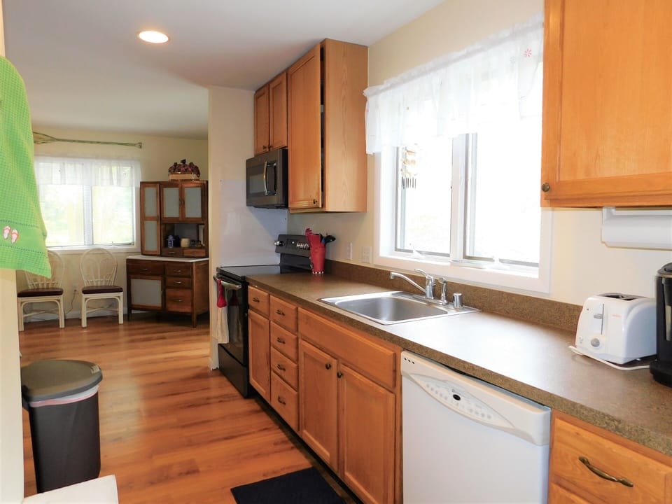 451 D Garfield Pkwy - Galley Kitchen - View of the functional kitchen featuring wood cabinetry, a white dishwasher, and a black stove.