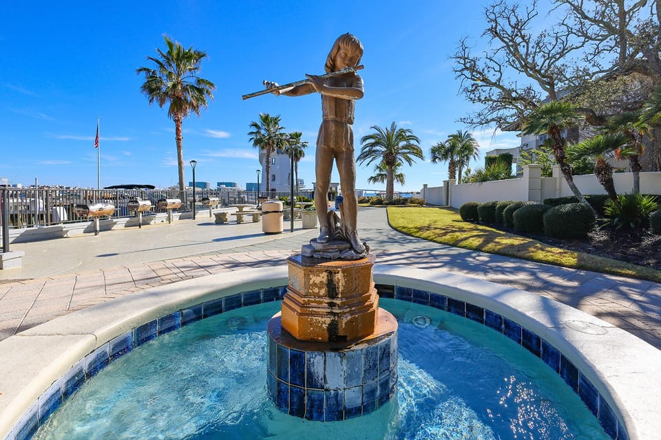 Enjoy this charming fountain featuring a flutist statue, surrounded by palm trees and a serene bay view