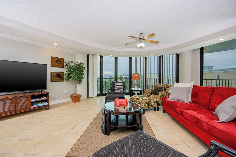 Spacious living area featuring a red sofa with queen sleeper, tropical accents, and expansive windows for a lovely view