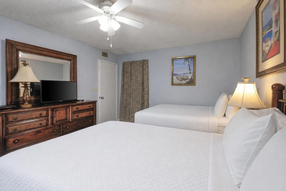 This cozy guest bedroom features two full beds, a flat-screen TV, and charming artwork to enhance your stay