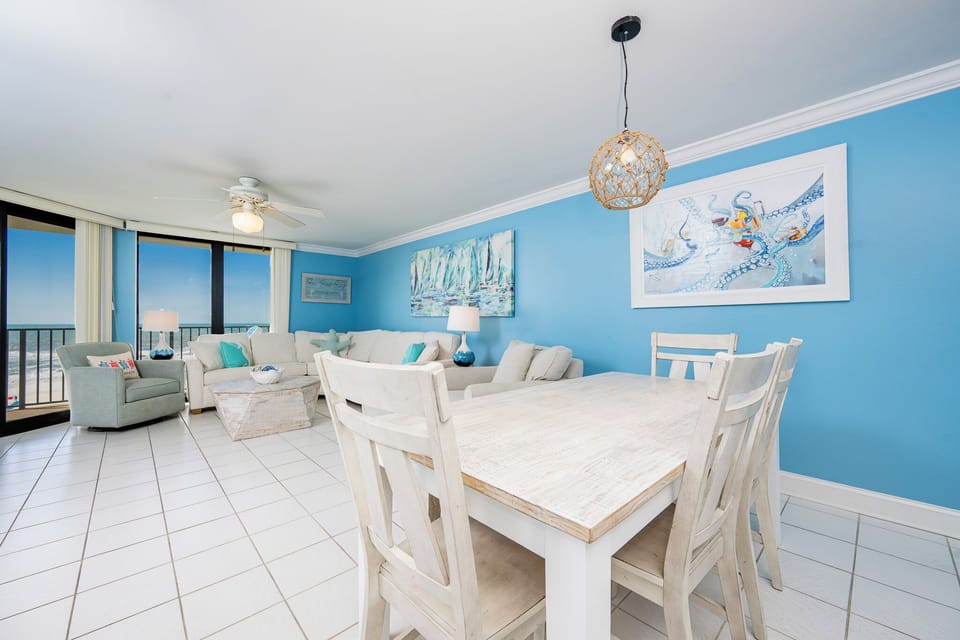 Coastal living area features a light-filled space with a comfortable sofa, dining table, and views of the beach