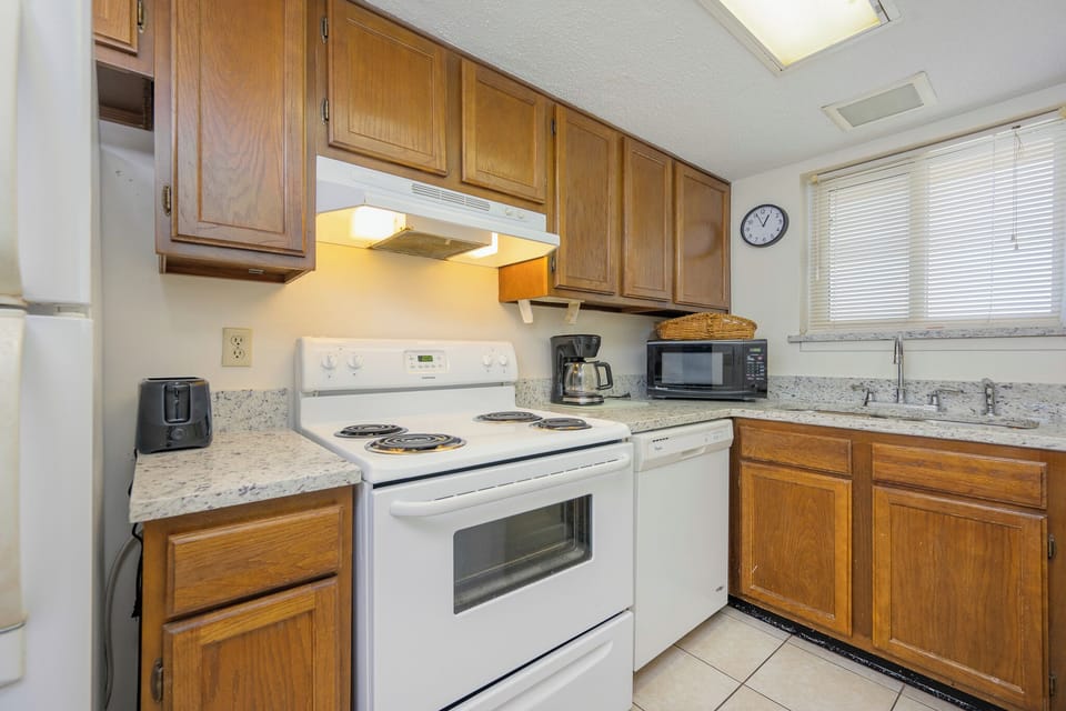 This kitchen features wooden cabinetry, essential appliances, and a cozy atmosphere perfect for meal preparation
