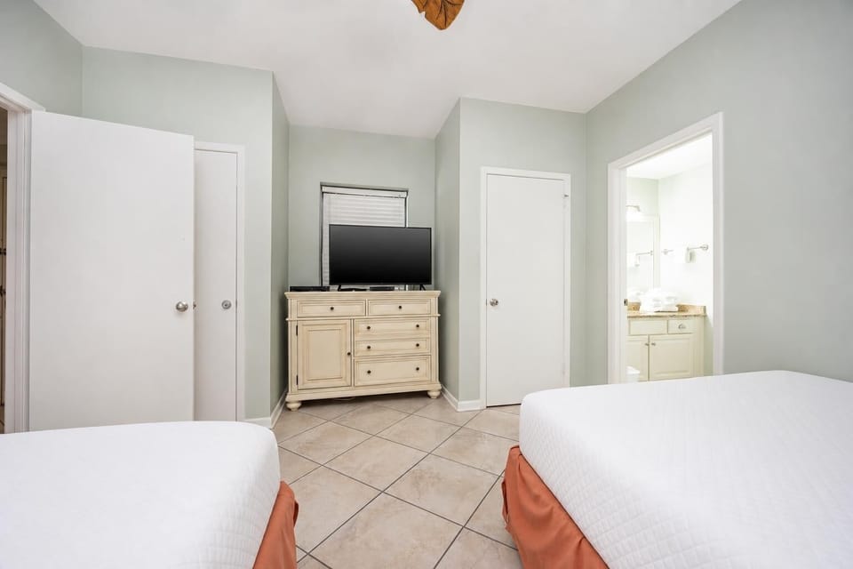 Relax in this guest bedroom with two queen beds, a TV, and easy access to the bathroom