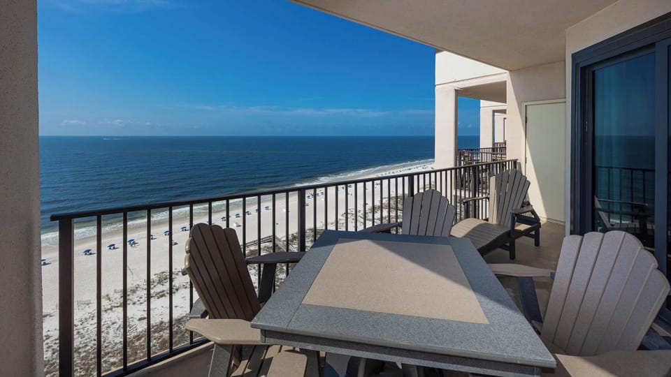 Relax on the balcony enjoying panoramic views of the tranquil waters and beach umbrellas below