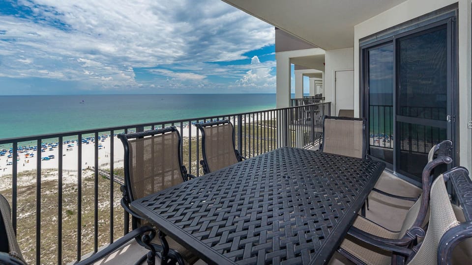 Dining table with seating on the balcony overlooks the beach and gulf, providing a perfect spot for meals and relaxation