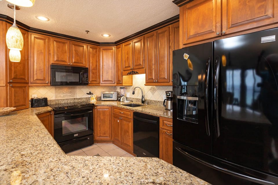 Wood cabinetry complements the granite countertops in this kitchen, featuring a breakfast bar and views of the gulf