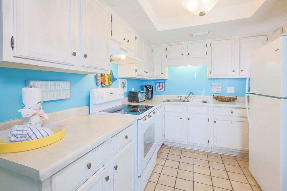 This kitchen features white cabinetry, a blue accent wall, stainless appliances, and a Keurig for your convenience