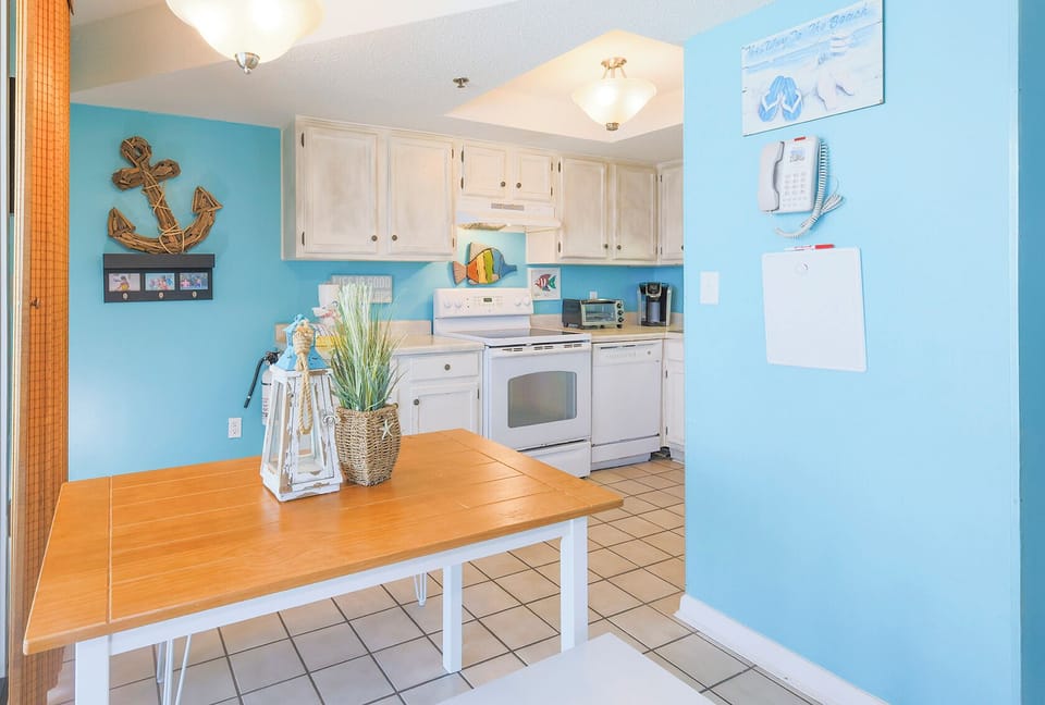 This cheerful kitchen features white cabinetry, stainless appliances, and a cozy dining area with a beachy vibe