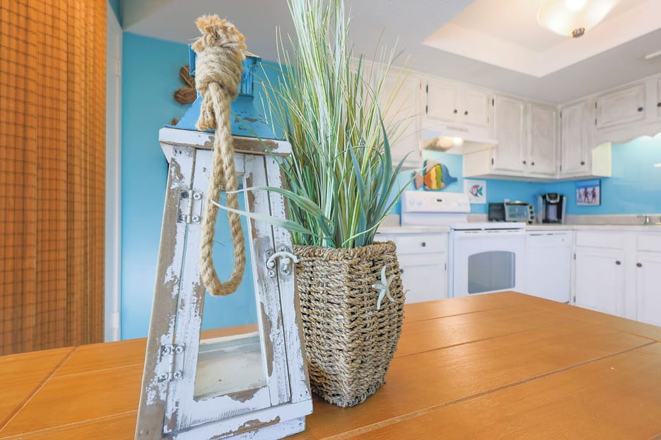 This kitchen features bright blue accents, a Keurig coffee maker, and charming coastal decor, perfect for your beach getaway
