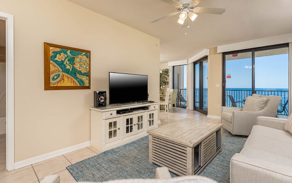 Relax in the inviting living area with a TV, sofa with queen sleeper, and views of the water beyond the glass doors