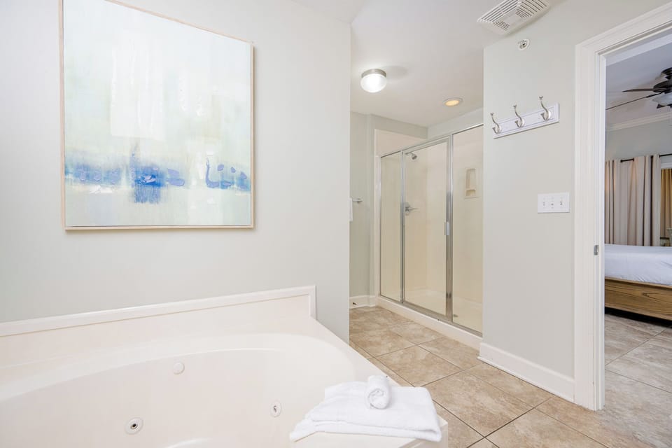 Refreshing master bathroom featuring a jetted tub, walk-in shower, and soothing artwork in soft blue tones