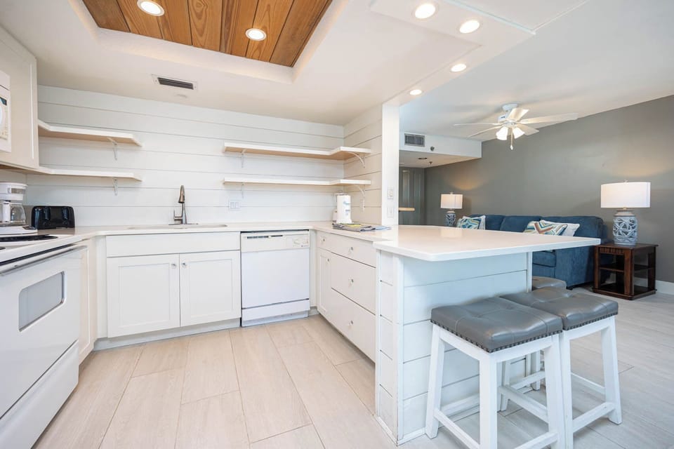 Bright, modern kitchen featuring white appliances and a cozy bar area with stylish seating, perfect for casual dining