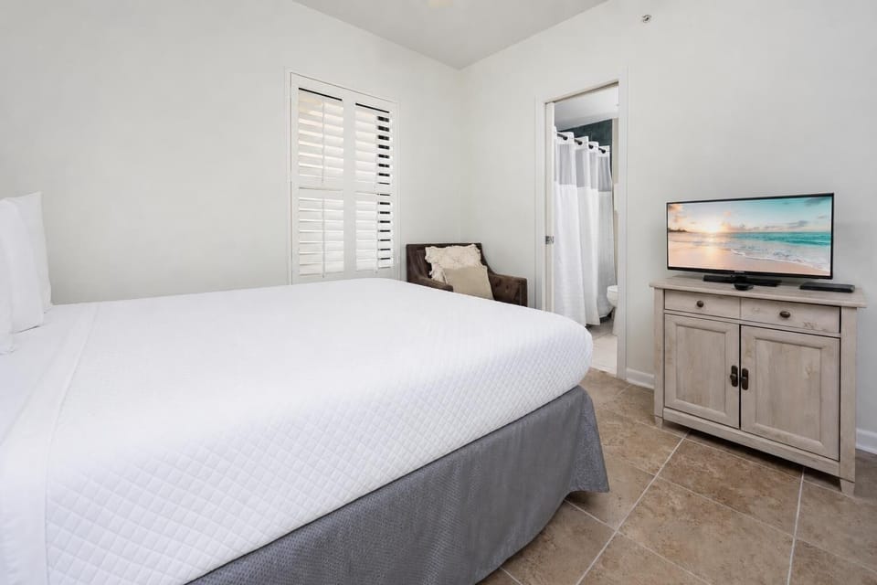 Inviting guest bedroom featuring a queen bed, a cozy chair, and a TV for your entertainment