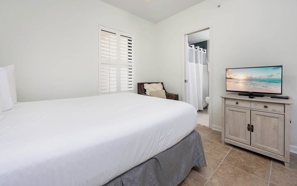 Inviting guest bedroom featuring a queen bed, a cozy chair, and a TV for your entertainment