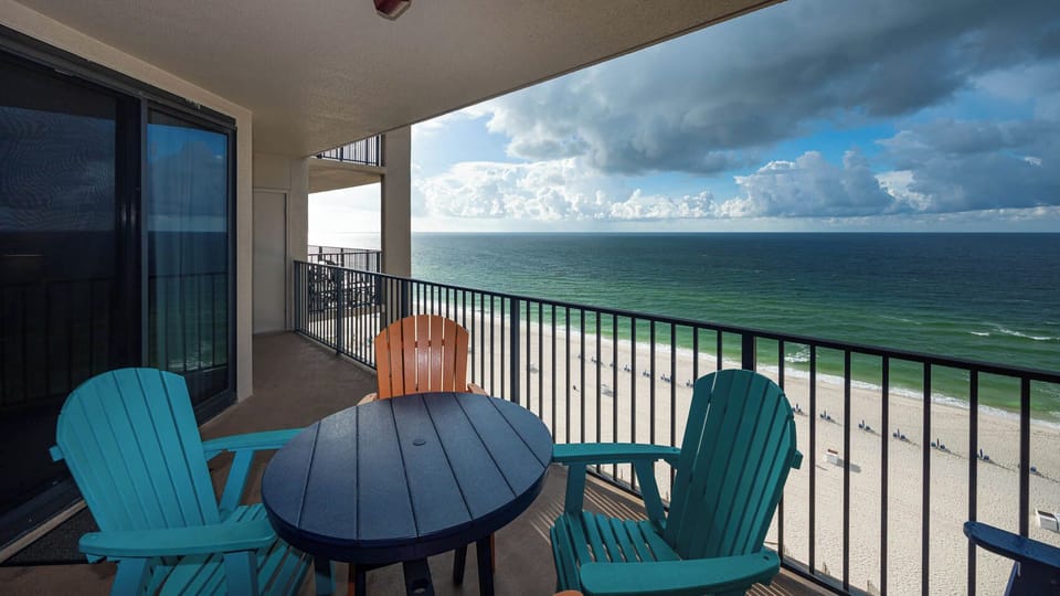 Relax on the balcony with colorful chairs and enjoy the expansive views of the water and beach below