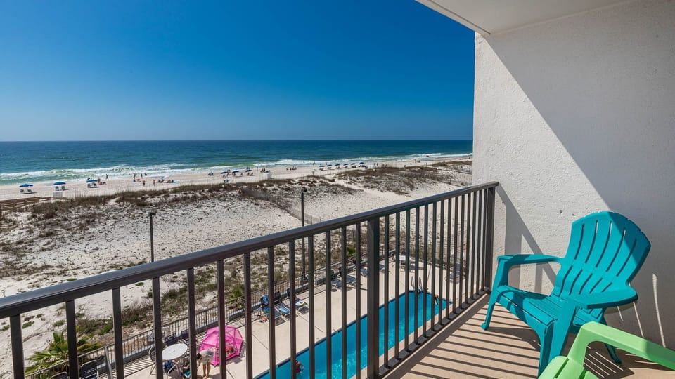 Enjoy a stunning beachfront view from the balcony, complete with vibrant teal chairs and a relaxing atmosphere