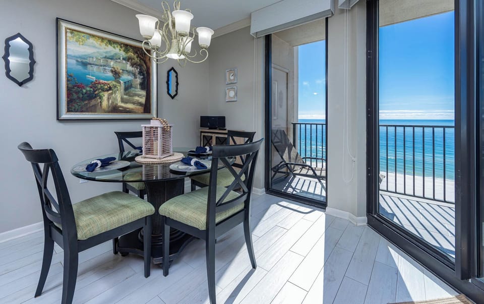 Dine at the glass table with plush seating, enjoying beautiful beach views through expansive windows