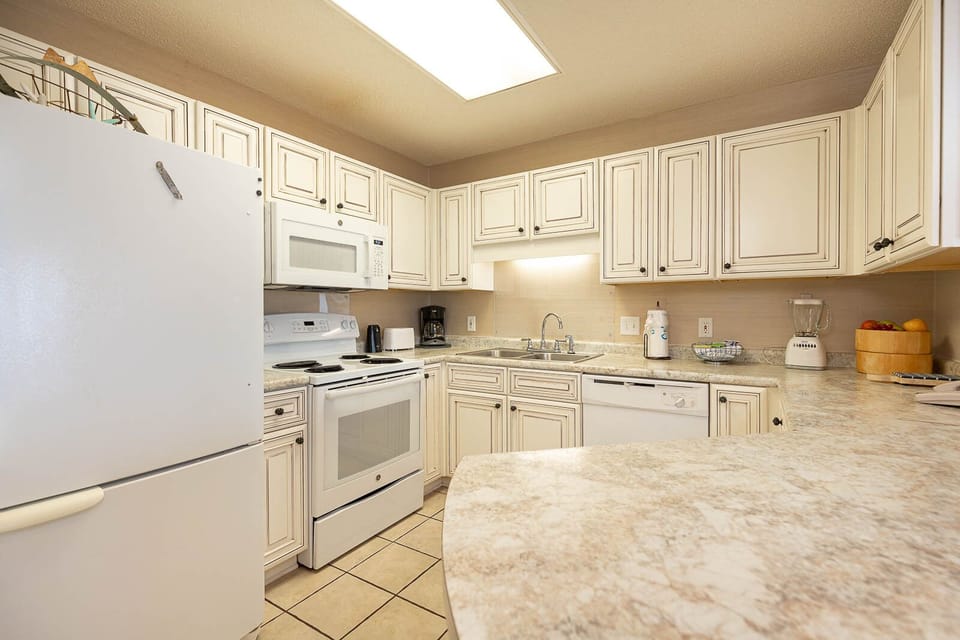 White cabinetry and granite countertops complement the modern kitchen, featuring essential appliances and ample workspace