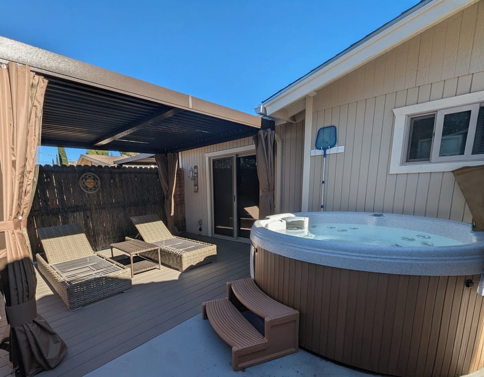 Rear patio with shade pergola, lounge chairs, and hot tub. Serenity awaits!
