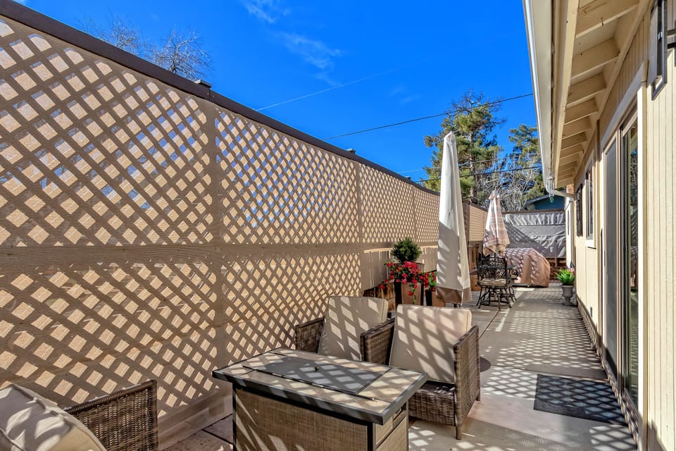 Side patio with fire pit, barbecue, and dining table with umbrella