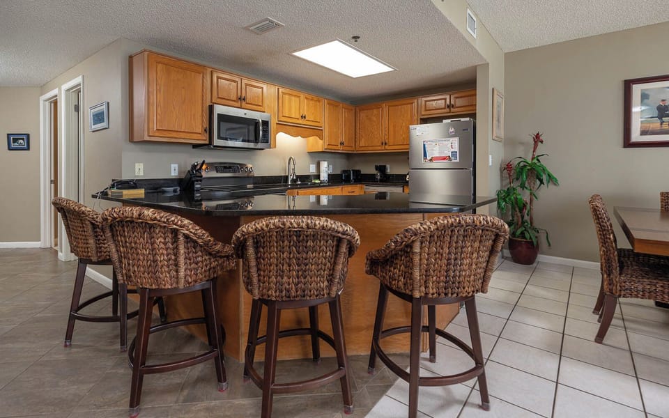 Warm wood cabinetry complements the sleek black countertops and stainless appliances in this inviting kitchen area
