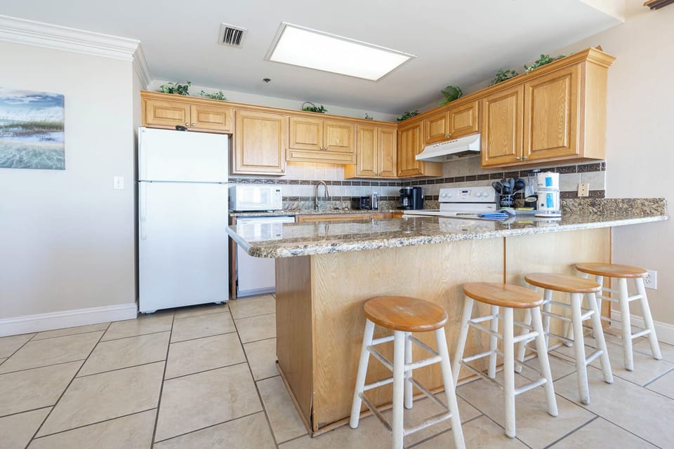 Prepare meals in this kitchen featuring granite countertops, ample storage, and a breakfast bar for casual dining