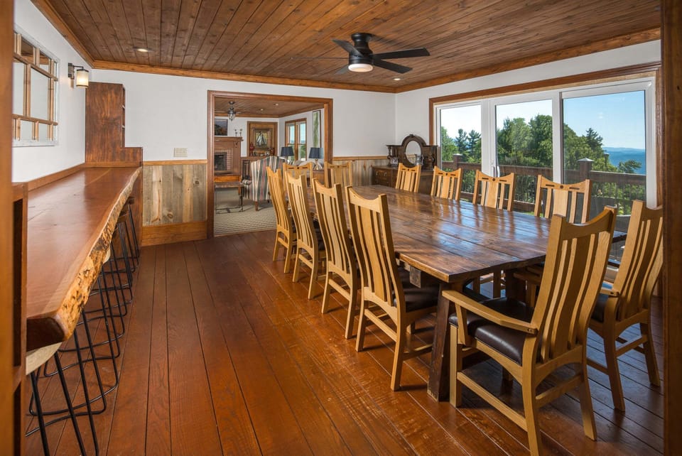 Spacious dining room with a large banquet table, live-edge bar seating, and mountain views