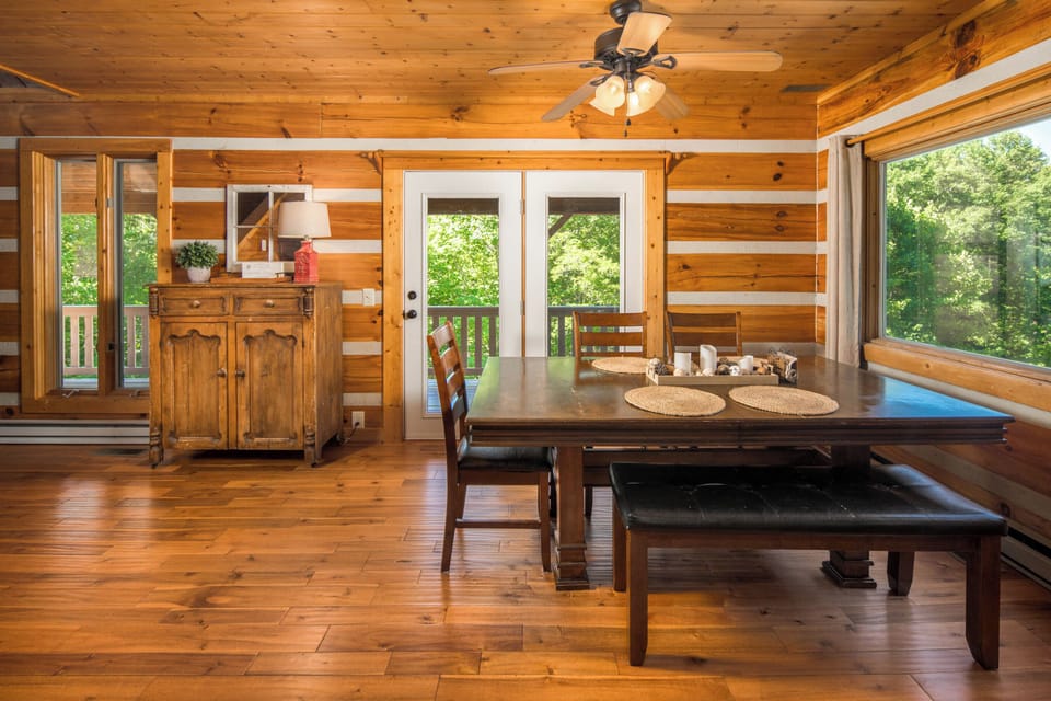 Dining table with seating for six surrounded by natural light and wooded views