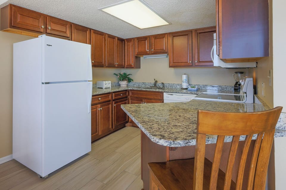 Prepare meals in this inviting kitchen featuring wooden cabinetry and granite countertops