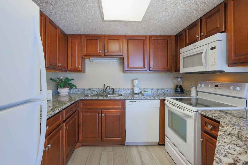Granite countertops, wooden cabinetry, and white appliances adorn this inviting kitchen