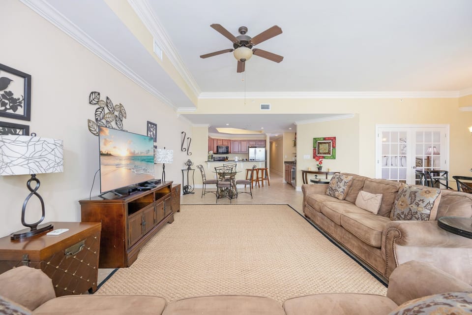 Spacious living area with comfortable seating, a large TV, queen sofa-sleeper, and a view into the modern kitchen