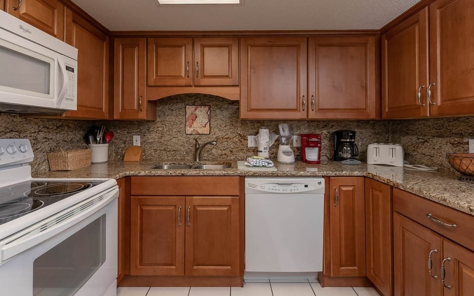 Granite countertops complement this kitchen, featuring essential appliances, a Keurig, coffe maker, and a breakfast bar