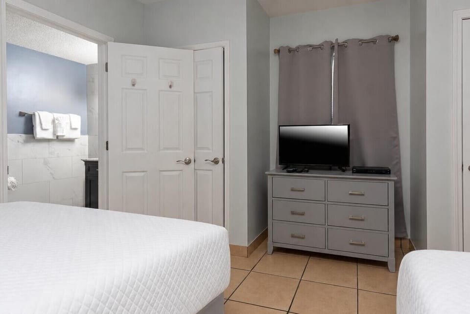Inviting guest room featuring two cozy queen beds, a TV, and easy access to a stylish bathroom with fresh towels