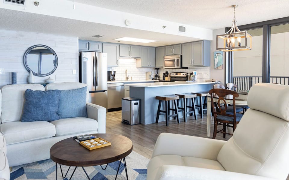 Living area featuring a comfortable sofa with queen sleeper, a stylish coffee table, and a kitchen with a breakfast bar