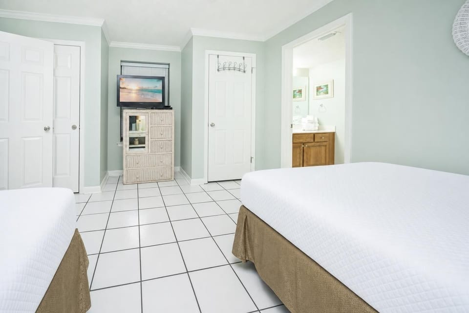 Inviting guest room featuring two beds, a TV, and easy access to the bathroom with fresh towels