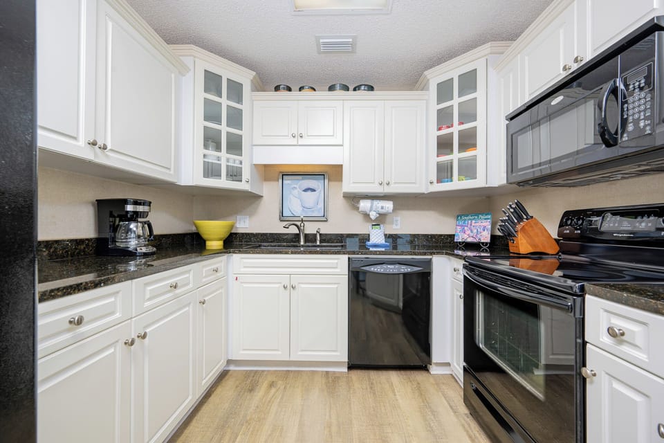 White cabinetry, black appliances, and a vibrant yellow bowl in this kitchen create a welcoming cooking space