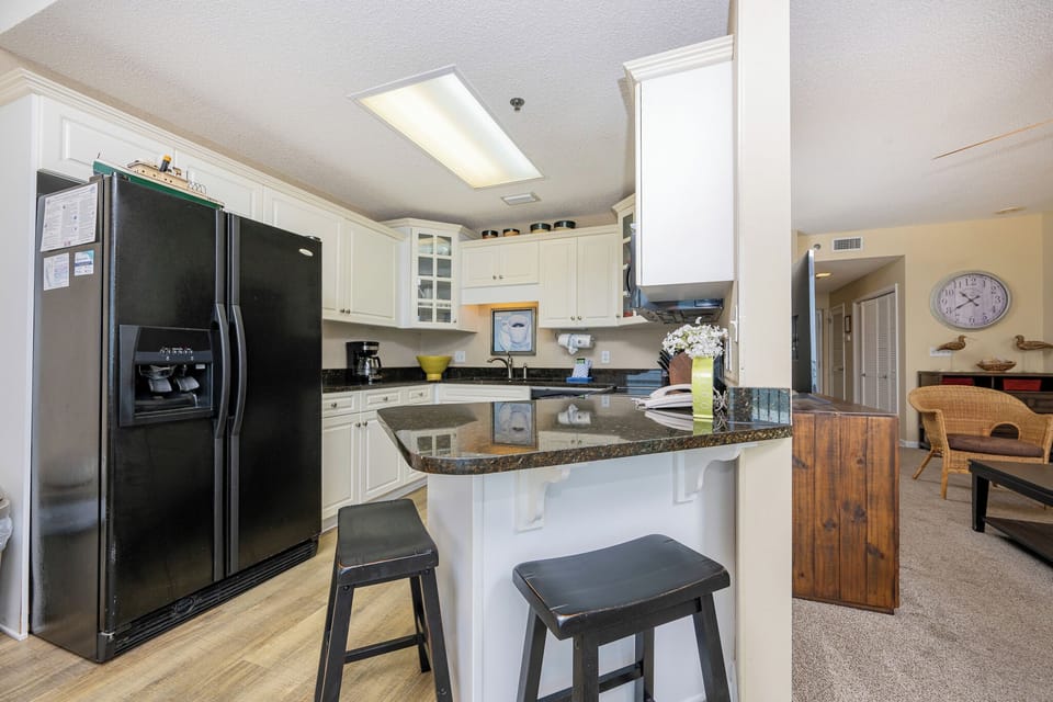 Modern kitchen features black appliances, granite countertops, and a breakfast bar with seating, creating a welcoming space