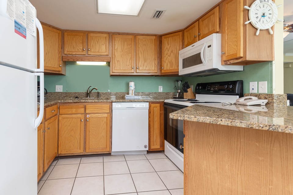 The kitchen features light wood cabinetry, granite countertops, and white appliances