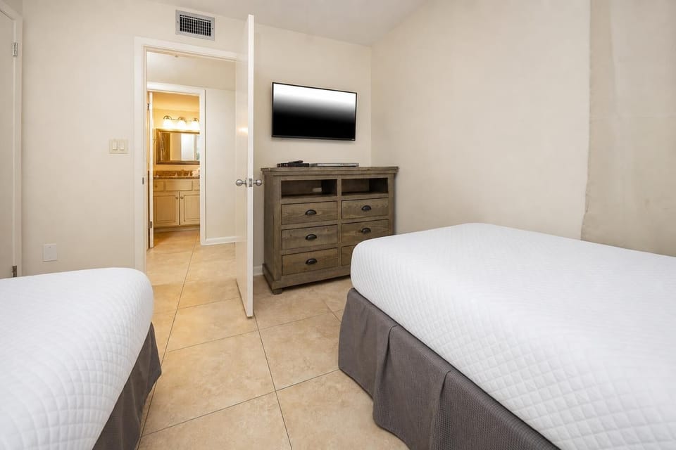 This cozy bedroom features two twin beds, a flat-screen TV, and an adjoining bathroom for your convenience