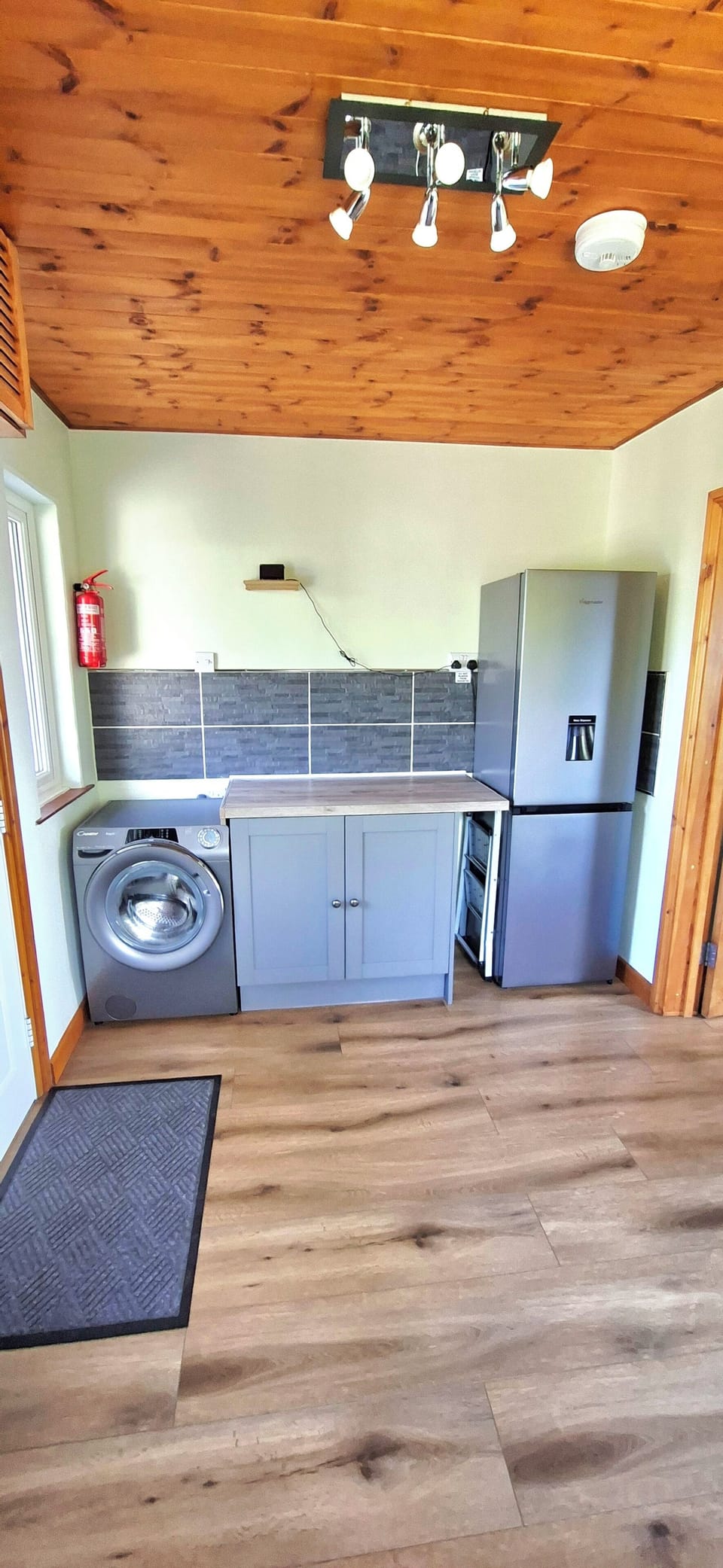 Spacious utility room with washing machine and fridge/freezer.