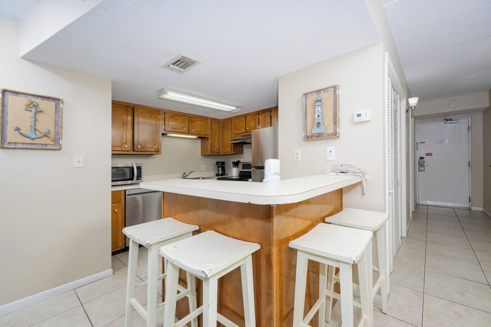 The kitchen features warm wooden cabinetry, a breakfast bar with seating, and convenient appliances for meal prep