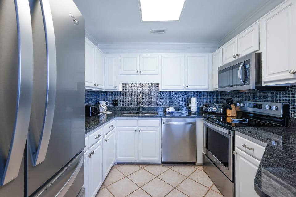 White cabinetry complements the sleek granite countertops in this modern kitchen, featuring a convenient breakfast bar area
