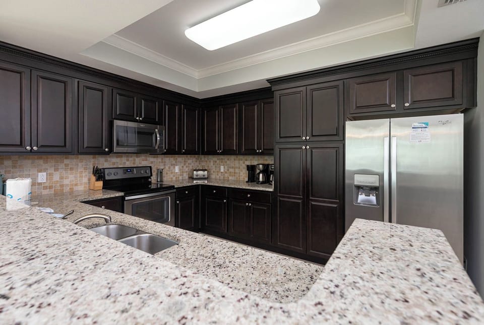 Prepare meals in this stylish kitchen featuring dark cabinetry, granite countertops, and stainless appliances
