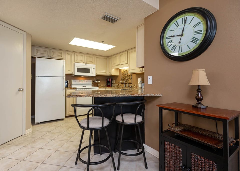 The fully-equipped kitchen features granite countertops, a breakfast bar with seating, and elegant decor accents